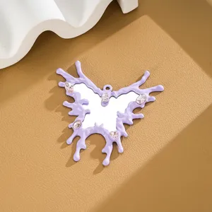 Close-up of irregular butterfly mirror pendant with lavender drip edges and gemstones