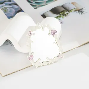 Dettaglio dello specchio con cornice fluida crema e pietre preziose a cuore rosa