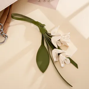 Detailaufnahme eines grün-weißen Taschenanhängers aus PU-Leder in Lilienform für Damen