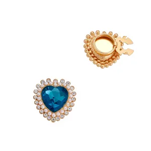 Dettaglio del gemello a forma di cuore con cristallo blu, perle e strass luccicanti.