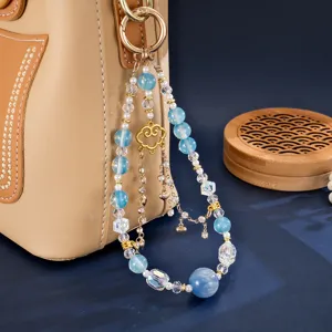 Detail of elegant gold foil bead charm with blue beads and heart pendant on bag