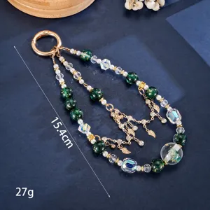 Detail view of handmade phone charm with green gold-foil beads and gold leaf pendants