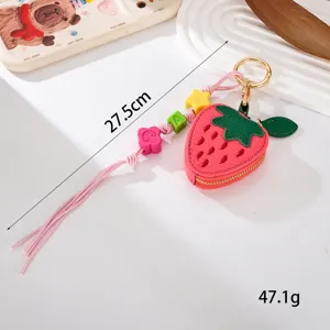 Détail d'une élégante mini pochette en cuir en forme de fraise avec cordon perlé.