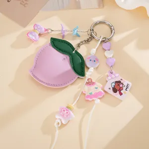 Détail rapproché d'un joli bijou de sac en cuir PU en forme de pêche avec pendentifs chiots