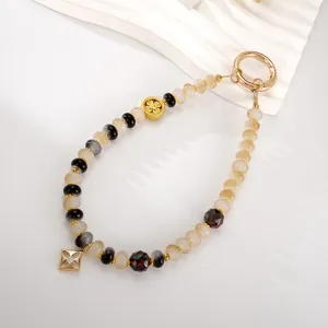 Detailed macro view of a beaded phone wrist strap with square gold pendant and clasp.