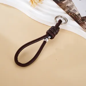 Detail of handmade woven dark brown leather rope keychain with silver bead and knot