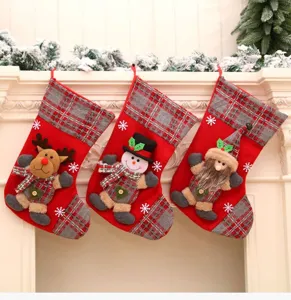 Grandes chaussettes de Noel en peluche avec renne et bonhomme de neige pour decor.