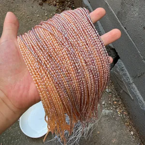 Nahaufnahme von 2-2,5 mm farbigen Süßwasser-Reisperlen-Strängen in der Hand