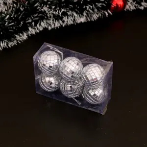 Gros plan de boules disco argentées dans une boîte transparente pour sapin de Noël.
