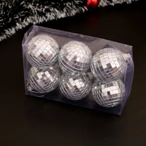 Gros plan détaillé de boules à facettes argentées dans une boîte transparente pour sapin.