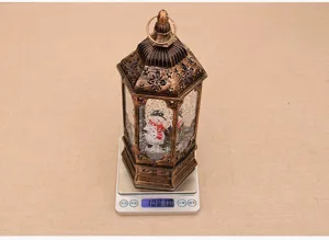 Detail view of Christmas water snow globe lantern showing weight on scale, festive decor.
