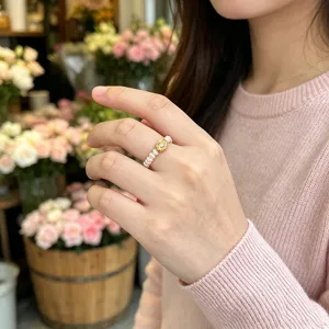Detailansicht eines elastischen Süßwasserperlenrings mit Goldbarren-Anhänger am Finger