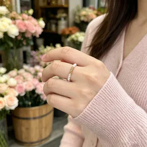 Detailansicht eines Rings aus echten Süßwasserperlen mit Goldperlen an einer asiatischen Hand.