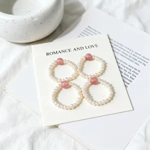 Detail of elastic freshwater pearl rings with pink strawberry crystal beads on a card
