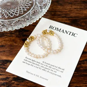 Detailansicht eines Süßwasserperlen-Elastic-Rings mit goldenem Ährenmotiv auf Karte