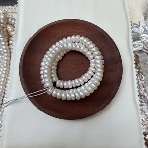 Top-down view of natural white button pearls on a dark wooden display plate