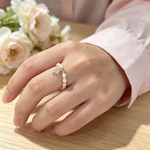 Detailaufnahme eines elastischen Süßwasserperlenrings mit goldenem Sternanhänger.