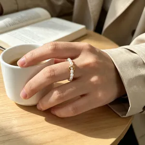 Detaillierte Nahaufnahme des eleganten Perlrings mit goldenem Element in der Mitte.
