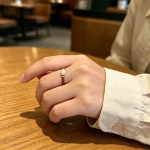 Nahaufnahme eines Rings aus rotem Achat und Süßwasserperlen an einem Finger in einem Café