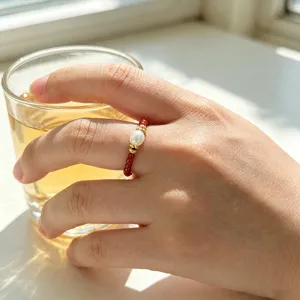 Nahaufnahme eines handgefertigten elastischen Rings mit Süßwasserperle und rotem Achat am Finger