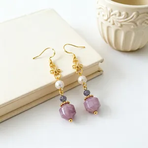 Detailed view of Chinese style pearl and purple crystal earrings with gold bow accents.