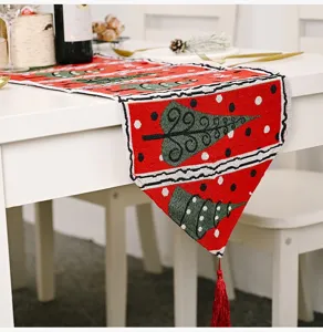 Detailansicht des Weihnachtstischläufers, roter Strickstoff mit grünem Baummotiv und Quaste.