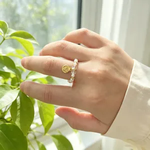 Nahaufnahme des elastischen Süßwasserperlenrings mit Bergkristallen und Goldmünze