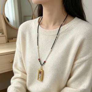 Primer plano de un collar largo con colgante Thangka llevado por una modelo sobre jersey blanco