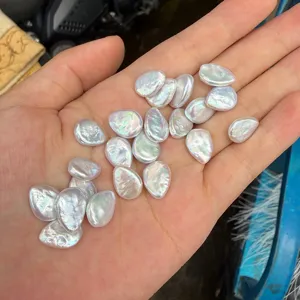 Vista macro de perlas barrocas de gota iridiscentes sostenidas en la mano para escala