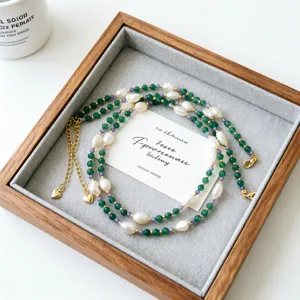 Détail du collier en pierre naturelle verte et perles baroques dans un plateau en bois
