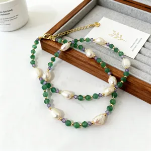 Gros plan d'un collier en pierres vertes et perles baroques sur un plateau à bijoux