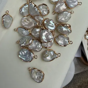 Vue détaillée de pendentif perle d'eau douce baroque, forme irrégulière bordée d'or.