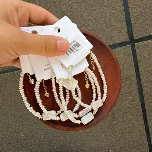 Close-up of irregular square Baroque pearl bracelets with golden heart charms on cards