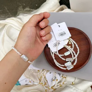 Macro detail of white gum square Baroque pearl bracelet on wrist and wooden tray