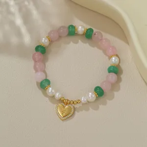 Nahaufnahme des Perlen- und Kristallarmbands mit goldenem Herzanhänger für elegante Modeschmuck.