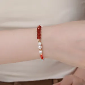 Nahaufnahme des eleganten Naturperlen und roten Cinnabar Perlenarmbands mit Goldelementen.