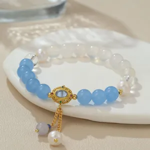 Nahaufnahme Detail des chinesischen Perlenarmbands mit blauen Steinen und goldenem Anhänger.