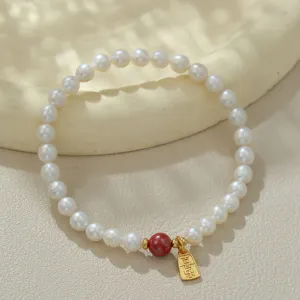 Elegantes Süßwasserperlenarmband mit rotem Zinnoberperlen- und goldenem Glücksanhänger.