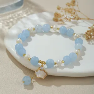 Nahaufnahme des Perlenarmbands mit Süßwasserperlen, blauen Kristallen und Muschelanhänger.