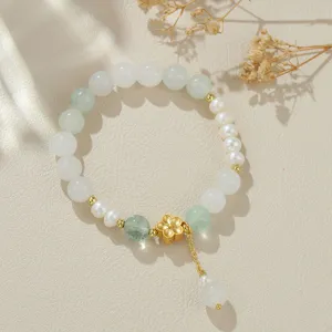 Elegantes Süßwasserperlen Armband mit grüner Kristallperle und goldenem Blumenanhänger.