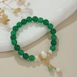 Detailaufnahme des grünen Perlenarmbands mit Süßwasserperlen und goldenen Elementen auf Keramikteller.