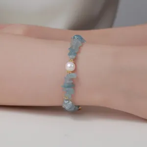 Detailopname van edelsteen splinter en zoetwaterparel armband gedragen om pols, frisse modestijl.