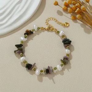 Gedetailleerd overzicht van gekleurde zoetwaterparel en kristallen armband met goud.