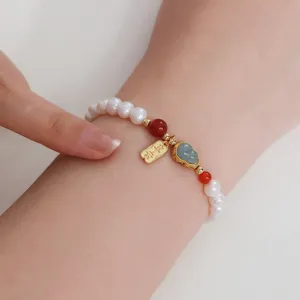 Detaillierte Nahaufnahme des natürlichen Perlenarmbands mit grünem Jadekürbis und Anhänger.