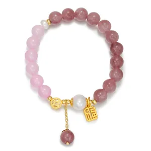 Gros plan détaillé du bracelet de perles en agate rose dégradée avec des breloques chanceuses.