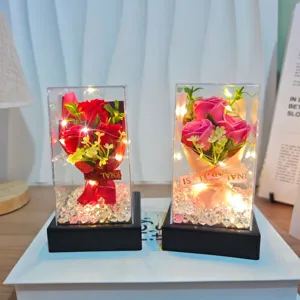 Artificial rose flower bouquet in clear acrylic gift box with LED string lights for home decor.