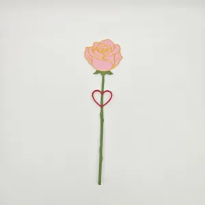 Dettaglio del magnete da frigo decorativo a forma di rosa con stelo verde e cuore rosso.