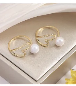 Nahaufnahme des vergoldeten offenen Rings mit Herzlinien-Design und eleganter weißer Perle.
