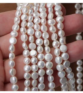 Detailed view of smooth coreless white coin freshwater pearls for DIY jewelry making.