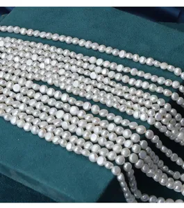 Close-up detail of natural freshwater tablet pearl loose strands, smooth white DIY jewelry making.
